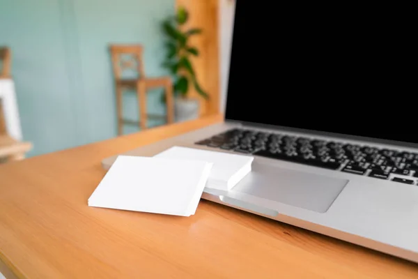 Blank business cards and laptop on wooden surface — Stock Photo, Image