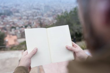 holding arka plan bulanık Barcelona şehir manzarasına sahip boş açık kitap erkek eller