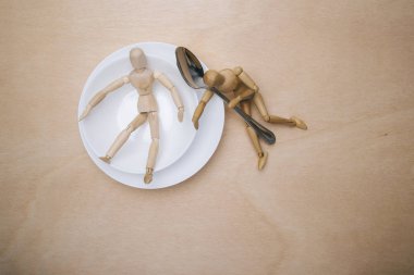 wooden mannequins couple in white plate with spoon. nutritional concept clipart