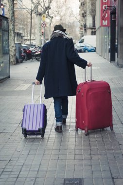 Genç adam şapkalı ve ceket ile kentsel sokakta seyahat çanta kış döneminde