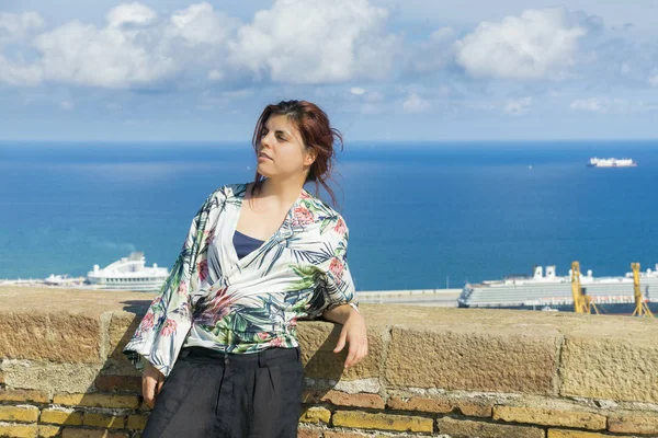 Woman standing in tourist place with cloudy sky and port view on background