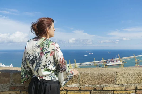 Woman standing in tourist place with cloudy sky and port view on background