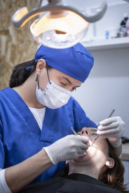 Kadın dişçi hasta üzerinde çalışıyor.