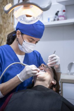 Kadın dişçi hasta üzerinde çalışıyor.