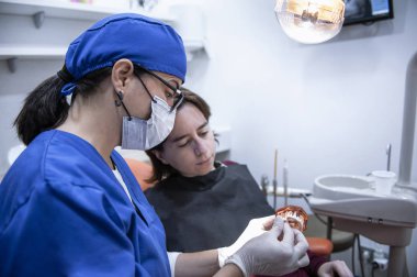 bir hasta ile konuşan kadın diş hekimi