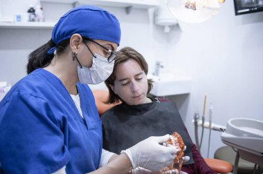 bir hasta ile konuşan kadın diş hekimi