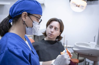 bir hasta ile konuşan kadın diş hekimi