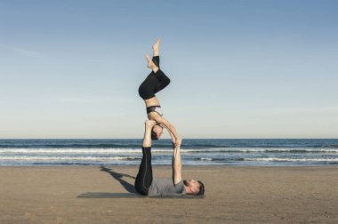 Genç çift akroyoga çalışıyor.