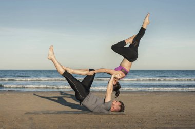 Genç çift akroyoga çalışıyor.