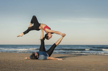 Genç çift akroyoga çalışıyor.