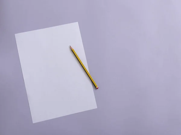 Papel blanco con lápiz sobre fondo violeta . — Foto de Stock