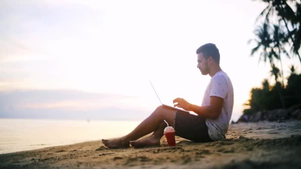 Jonge Knappe Man Bezig Met Een Laptop Het Strand Ondergaande — Stockvideo