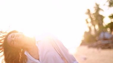 Günbatımında bir tropik ada kıyı yürüyen güzel genç kadın.