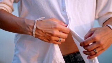 Genç bir kadın beyaz bir gömlek, sıkı bir göbek açığa unbuckles.