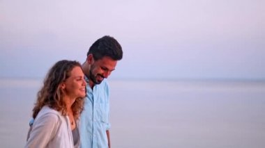 Genç, güzel bir kaç gün batımında bir kucaklama deniz kıyısı boyunca yürüyüş. Adam ve kız bir tropik adada balayına.