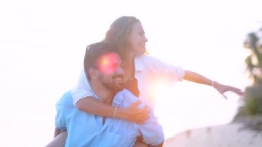 Genç, güzel bir kaç gün batımında bir kucaklama deniz kıyısı boyunca yürüyüş. Adam ve kız bir tropik adada balayına.