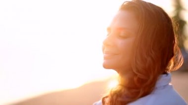 Genç, güzel kadın, kumlu bir plaj üzerinde oturur ve mesafe içine görünüyor. Mutlu kız erkek arkadaşını bekleyen denizin kenarında oturan.