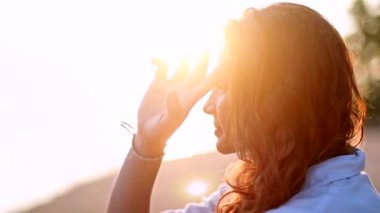 Genç, güzel kadın, kumlu bir plaj üzerinde oturur ve mesafe içine görünüyor. Mutlu kız erkek arkadaşını bekleyen denizin kenarında oturan.