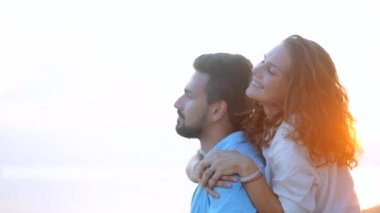 Genç, güzel bir kaç gün batımında bir kucaklama deniz kıyısı boyunca yürüyüş. Adam ve kız bir tropik adada balayına.