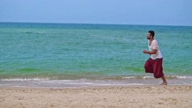 Genç ve yakışıklı bir adam tropik bir adada sahil boyunca çalışıyor.