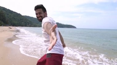 Genç ve yakışıklı bir adam tropik bir adada sahil boyunca çalışıyor.