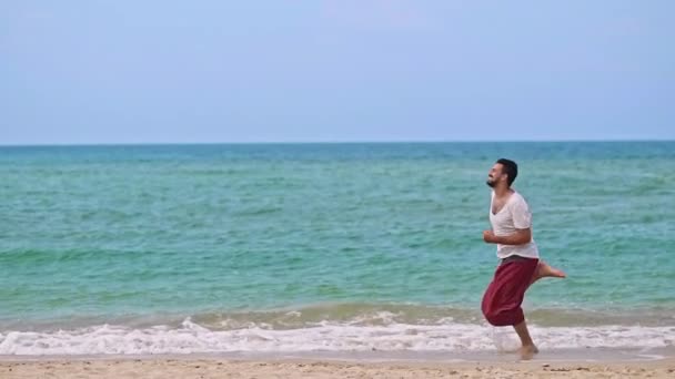 一个年轻英俊的男人在热带岛屿上的海滩上奔跑 — 图库视频影像