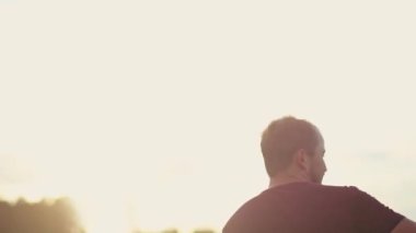 Bir parkta mutlu bir şekilde dinlenerek yakışıklı bir genç adam. Gün batımında açık havada sevimli adam kandırmak.