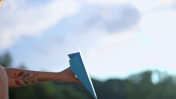 一个手上有纹身的年轻美丽女孩发射纸飞机 美丽的女人 在户外的自然 在日落时 发射彩色纸飞机 — 图库视频影像