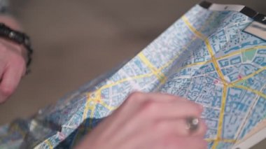 Yakın çekim eller rotayı kağıt haritada gösterir. Şehrin açık havada, turistler şehrin bir harita için önünü. Beyaz tenli adam parmağını haritaya doğrulttun. Bir erkek ve bir kadın haritaya bakar ve yolu tartışır..