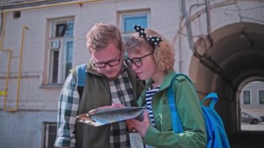 Genç, güzel turistler yaz aylarında eski şehirde dolaşmak ve haritabakmak. Turistler şehirde kayboluyor. Rota seçimi. Kağıt haritada bir yol arayın. Birlikte seyahat etmek. Genç bir aile. Sevgi dolu bir çift turist dünyayı dolaşıyor.