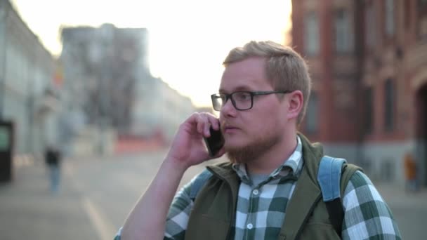 街上一个年轻英俊的芬兰男人正在打电话 一个男人用手机对人发誓 一个年轻的商人通过电话解决问题 在手机上进行攻击性对话 — 图库视频影像