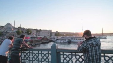 Türk balıkçı köprüde. Türk bayrağı rüzgarda dalgalanıyor. İstanbul 'da balık tutmak. Gerçek insanların hayatı. Boğaz manzarası var. Cami manzarası. Şehir su taşımacılığı yolcuları taşıyor.