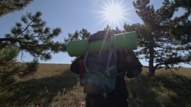 Genç, erkek bir turist dağlara tırmanıyor. Sırtında sırt çantası olan bir gezgin dağın tepesinde duruyor. Güneşin doğuşunda deniz manzarası.