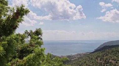Sahil manzaralı. Bulutların hareketi ve denizdeki suyun hareketi. Küçük, yat dalgalarda yüzüyor. Kıyı dağlarının manzarası küçük bitkilerle yerel olarak kuraklıktır..