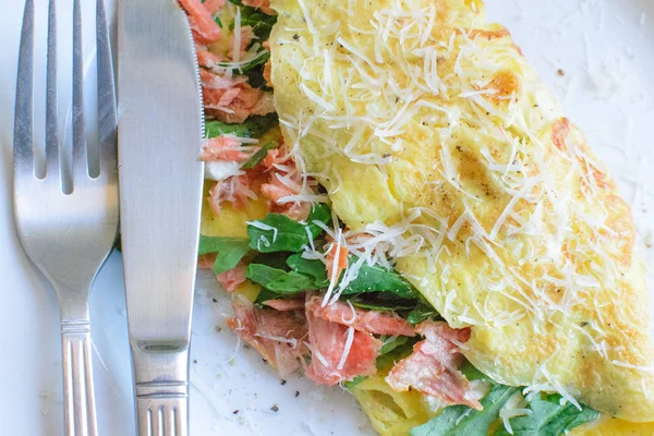 Fransız omlet beyaz bir tabak üzerinde. Roka, somon ve peynir omlet. Kahvaltıda omlet. Yakın çekim.