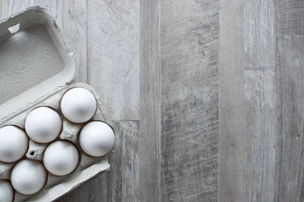 Ahşap masa üzerinde karton kutuda tavuk beyaz yumurta. Kopya alanı.