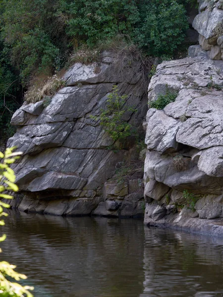 Big white rocks and forest behind lake. Rocks reflection in water.