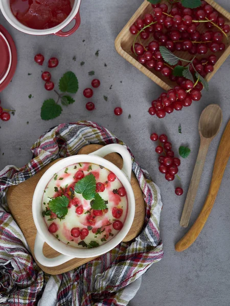 Sütlü pirinç lapası ile kahvaltı kırmızı frenk üzümü ve nane, kremalı sütlü sütlü sütlü puding veya Fransız kuarklı, ahşap tabakta kırmızı frenk üzümü / üst manzara.      