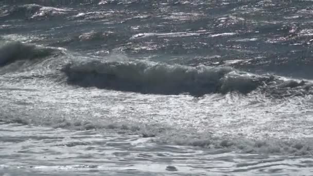 Vista de una hermosa playa de arena oceánica con las olas azules rodando en la orilla, algunas rocas presentes . — Vídeo de stock