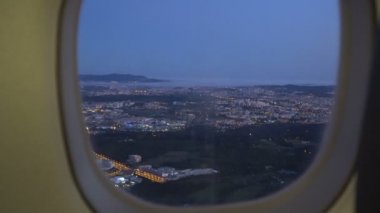 Gün batımında şehir penceresinden bir iniş uçağının görüntüsü.
