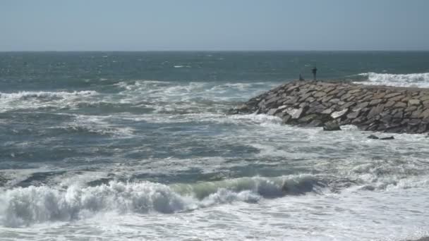 Vue sur une belle plage de sable de l'océan avec les vagues bleues se déversant dans le rivage, quelques rochers présents . — Video