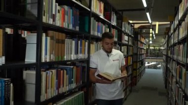 Genç kolej öğrenci alarak kitap raf Kitaplığı'nda. Yakışıklı delikanlı Kitaplığı'nda. Magdeburg, Almanya. 01.09.2018