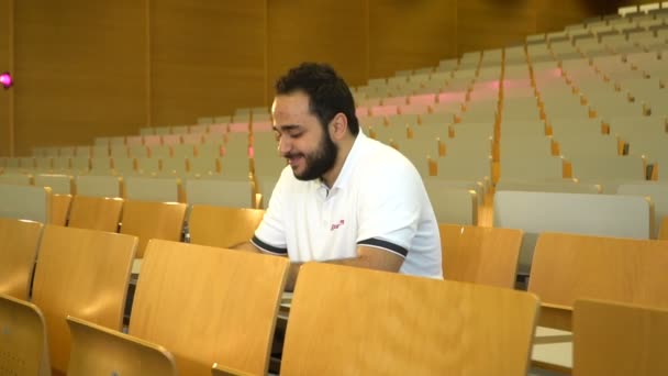 Retrato de un joven y atractivo estudiante sentado en la sala de conferencias, Magdeburgo, Alemania. 01.09.2018 — Vídeos de Stock