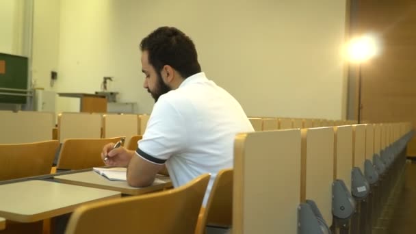 Портрет молодого привлекательного студента, сидящего в лекционном зале, Магдебург, Германия. 09 сентября 2018 года — стоковое видео