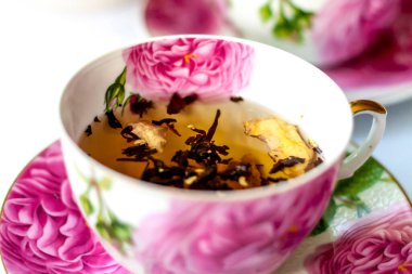 Bir fincan çay. Fincanda büyük çay yaprakları. Bir kutu çay. Meyveli büyük yaprak çayı.