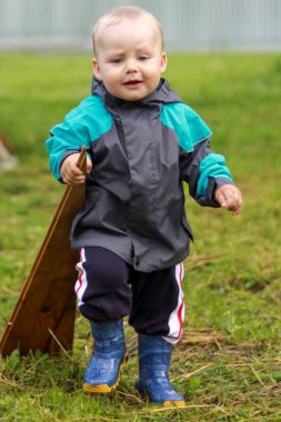 Çocuk elinde bir odun parçasıyla avluda koşuyor.