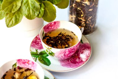 Bir fincan çay. Fincanda büyük çay yaprakları. Bir kutu çay. Meyveli büyük yaprak çayı.