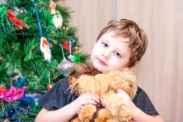 一个拿着玩具的男孩在圣诞树下 — 图库照片