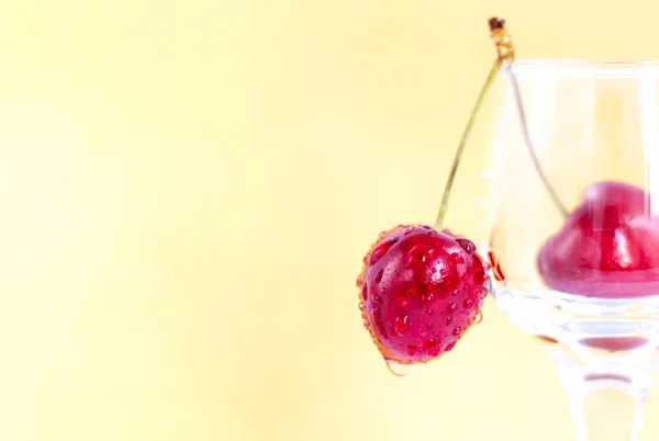 Sweet cherries. Red cherries hang on a transparent glass. Ripe berry. Bright summer background for presentations and graphic works.