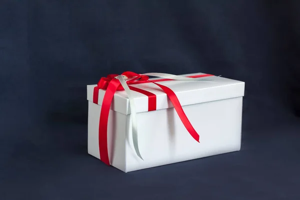 礼品盒是白色的 有漂亮的红色蝴蝶结 在黑暗背景下的礼物 假期和惊喜 缎子弓和莱茵石 — 图库照片